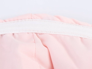 Détail macro du tissu en maille rose avec finitions élastiques blanches et coutures