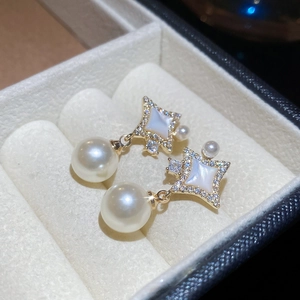 Vue détaillée de boucles d'oreilles étoile dorées avec perles et cristaux dans un écrin