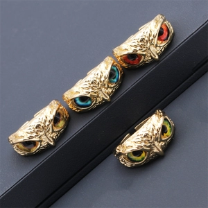 Detailed close-up of owl rings with colorful gemstone eyes in a gold-plated finish