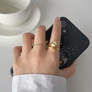 Detail of minimalist double-layered gold-plated rings in a modern liquid metal style