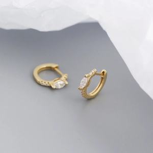 Macro shot of gold hoop earrings with marquise and round cut zircons on soft background