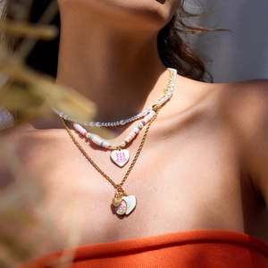 Détail de collier multi-rangs avec perles, perles arc-en-ciel et breloques coeur doré