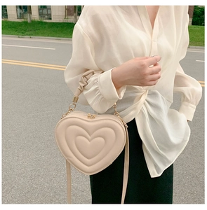 Detail of heart-shaped crossbody bag with smooth leather and gold-tone zippers