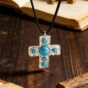 Macro view of vintage silver cross pendant with turquoise stones on rustic wood