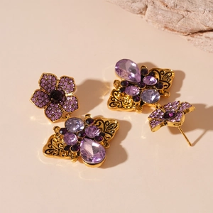 Retro gold earrings with purple crystal petals and butterfly drops on beige background