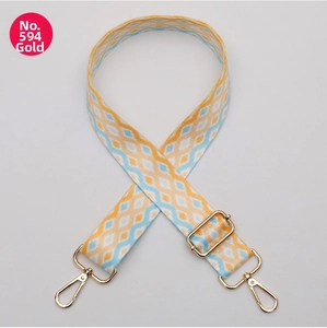 Macro detail of adjustable woven bag strap with geometric patterns and gold lobster clasps