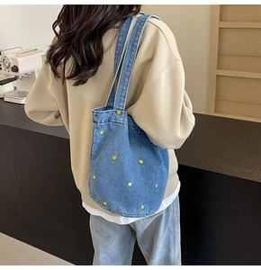 Détail d'un sac cabas en denim bleu avec broderies tulipes et bandoulière large