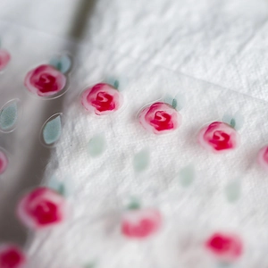 Japanese style floral nail stickers with pink roses on white textured fabric background