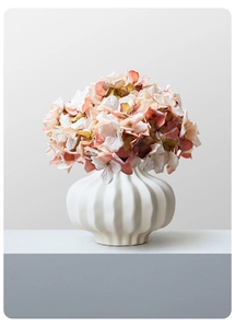 Detailed view of a white ceramic vase with vertical textures and realistic hydrangea flowers