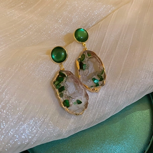 Detailed macro view of vintage irregular emerald green earrings with elegant gold plating