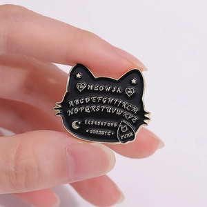 Retro black enamel bat cat brooch with gold Ouija board design shown held by hand