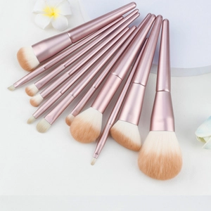 Draufsicht auf 10 roségoldene Make-up-Pinsel mit Farbverlauf auf Marmoroberfläche