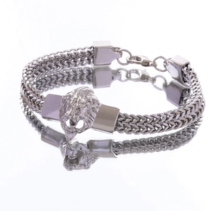 Detailed view of silver lion head men's wheat chain bracelet with lobster clasp closure