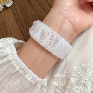 Detail of a white translucent geometric resin bracelet on wrist with lace sleeve