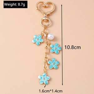 Detailed view of blue cherry blossom keychain with gold heart clasp and pearl pendant