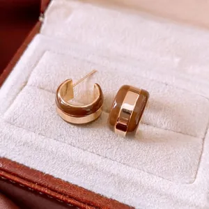 Classic gold-plated C-shaped hoop earrings with brown enamel stripes on a cream jewelry box