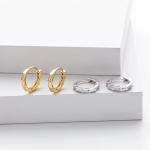 Detail view of gold and silver bamboo-shaped hoop earrings with sparkling cubic zirconia