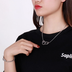 Silver handcuffs style necklace and bracelet set worn by a model on plain white background