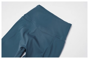 Detail of high-waist yoga pants with side pocket and flatlock seams in teal blue