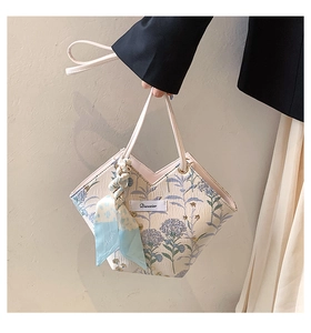 Close-up of beige canvas tote with blue floral prints and silk scarf on the handles