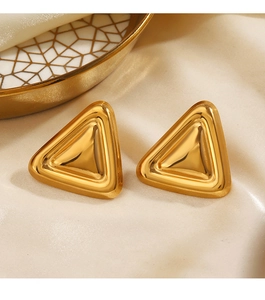 Gros plan de boucles d'oreilles triangle dorées sur soie et plateau en céramique