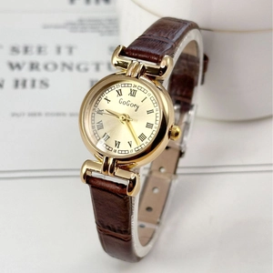 Vintage gold quartz watch for women with round dial and brown leather strap on white surface