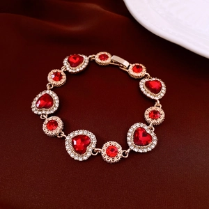 Vue macro du bracelet doré avec maillons cœur et pierres rouges sur velours