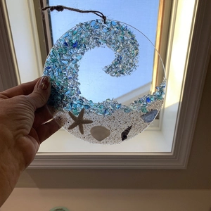 Detailed view of beach wave suncatcher with sea glass shell and starfish on sand
