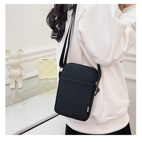 Detail of a black nylon crossbody bag with SPORT tag, shown on a white hoodie model