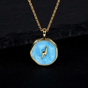 Detail of gold pendant with light blue enamel and golden lightning bolt on black rock