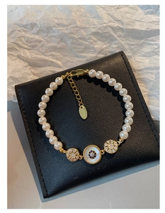 Vue macro détaillée du bracelet en perles plaqué or 18k avec œil porte-bonheur et fleurs