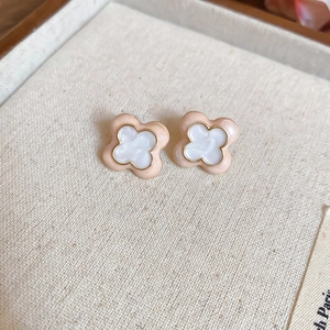 Macro view of pink clover earrings with gold edges on a soft jewelry box surface