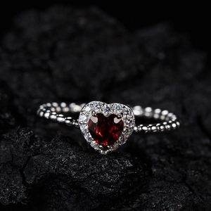 Macro shot of S925 sterling silver ring with heart-shaped garnet on black stone background