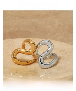 Detail of minimalist wavy stainless steel rings in gold and silver on marble