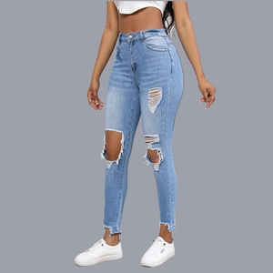 Close-up of high-waisted light blue distressed jeans with ripped details and frayed hems