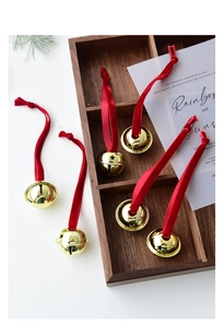 Detail of golden iron bells with red velvet ribbons arranged on a dark wooden tray