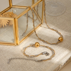 Detailed view of woven gold and silver necklace and bracelet set with golden bead charms