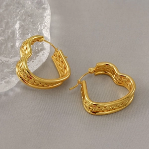 Minimalist gold heart earrings with twisted texture on a decorative crystal base