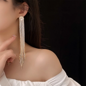 Close-up of model wearing long gold tassel earrings with shimmering cubic zirconia crystals