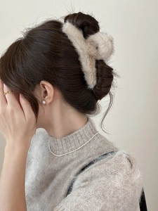 Vue latérale d'une grande pince à cheveux en fourrure de vison beige portée par un modèle