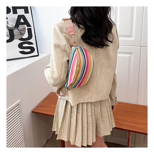 Detail of colorful woven straw waist bag with wide pink strap and bohemian stripes