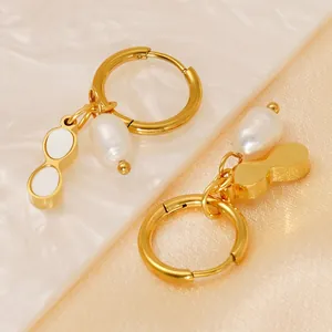 Detail of gold pearl earrings with baroque pearls and charms on satin fabric