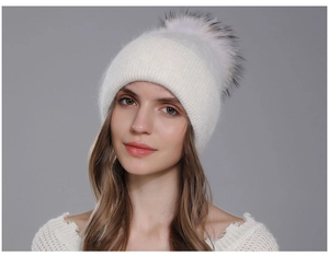 Detail of white knit beanie with fluffy oversized pom-pom and thick winter texture