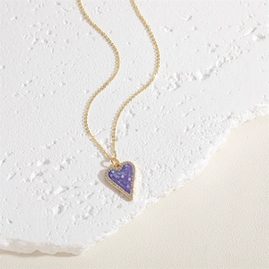 Detail of a gold heart pendant with purple mosaic shell inlay and white zircon crystals