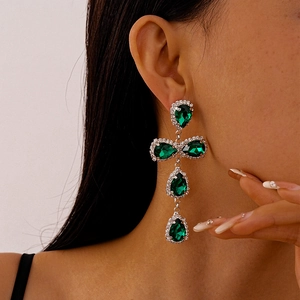 Detail of drop-shaped green gemstone earrings with sparkling tassels on model