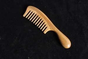 Macro detail of natural sandalwood comb with smooth wide teeth and elegant wood grain
