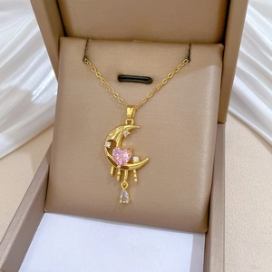 Close-up of gold moon necklace with pink heart gem in a premium gift box