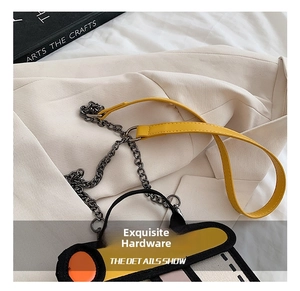 Detail showing the polished metal chain, yellow leather strap and 2D comic style bag texture