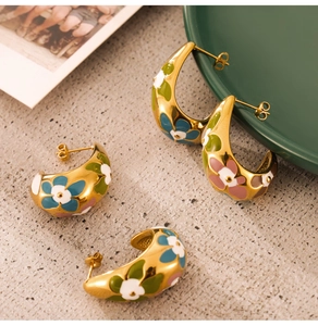 Artistic close-up of gold-plated enamel C-shape earrings with colorful floral patterns