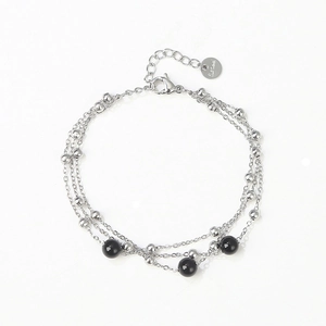 Detail of layered stainless steel bracelet with silver beads and black bead accents
